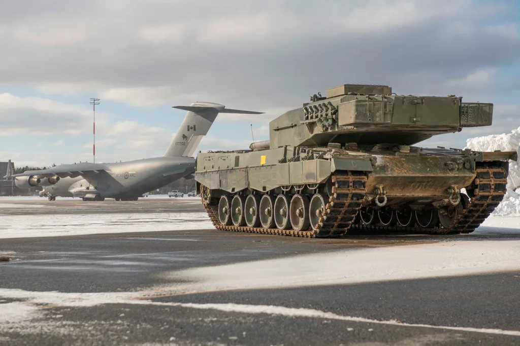 Kampfpanzer bereit zum Verladen und Weitertransport durch die auf dem Rollfeld wartende Boeing C-17 Globemaster der Royal Canadian Air Force.