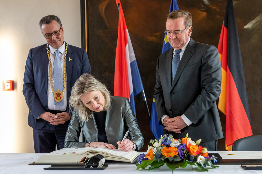 Die niederländische Verteidigungsministerin Kajsa Ollongren bei ihrer Unterschrift im Goldenen Buch und Gästebuch der Stadt Veitshöchheim. Links von ihr der erste Bürgermeister der Gemeinde, Jürgen Götz. Zu ihrer Rechten der deutsche Bundesminister der Verteidigung, Boris Pistorius.