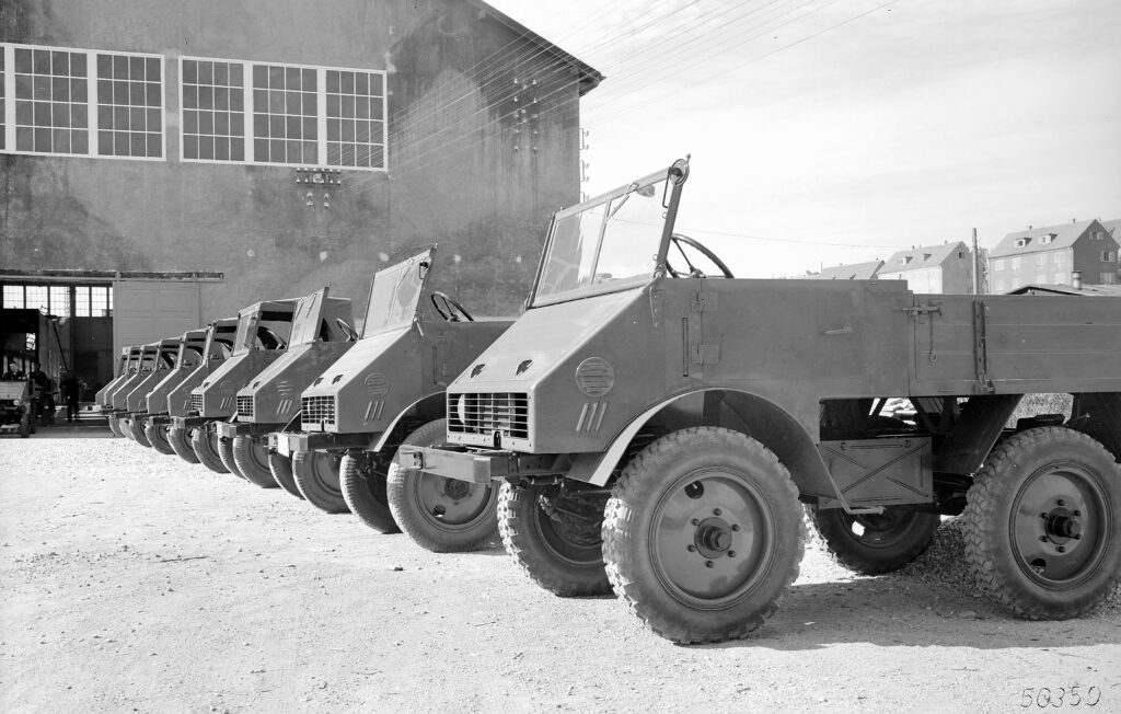 Aufnahme auf dem Firmengelände der Firma Boehringer in Göppingen. Im Hintergrund die Unimog-Halle, wo die Fahrzeuge gefertigt wurden. Anfangs wurden pro Woche sieben bis neun Fahrzeuge produziert. Ein interessantes Detail des dritten Fahrzeugs: Ein zusätzlicher Scheibenwischer auf der Beifahrerseite.