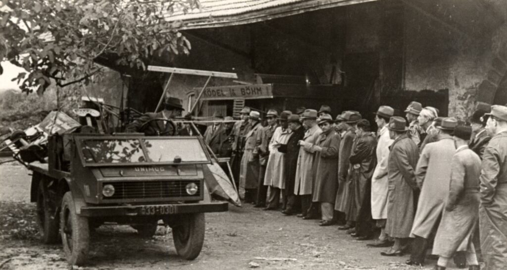 Der erste Serien-Unimog (Baureihe U 70200) mit Mähbinder und runtergeklappter Windschutzscheibe bei einer Vorführung vor Fachpublikum am 18. Oktober 1948 auf der Burg Staufeneck (Göppingen). Am Steuer ist Versuchsleiter Christian Dietrich.