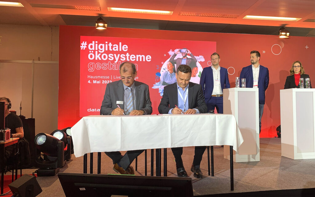 Unterzeichnung der Kooperationsvereinbarung auf der Dataport-Hausmesse (vorne v.l.n.r.): Dr. Johann Bizer, Vorstandsvorsitzender Dataport, und Dr. Martin Deeg, Senior Vice President Customer Solutions BWI; (hinten v.l.n.r.): Andreas Reckert-Lodde, Leiter der Arbeitsgruppe Cloud Computing und Digitale Souveränität und Projektgruppenleiter Zentrum für Digitale Souveränität Bundesministerium des Innern und für Heimat, Moritz Dörr, Programmleiter dPhoenixSuite Dataport, sowie Stefanie Dreyer, Moderatorin.