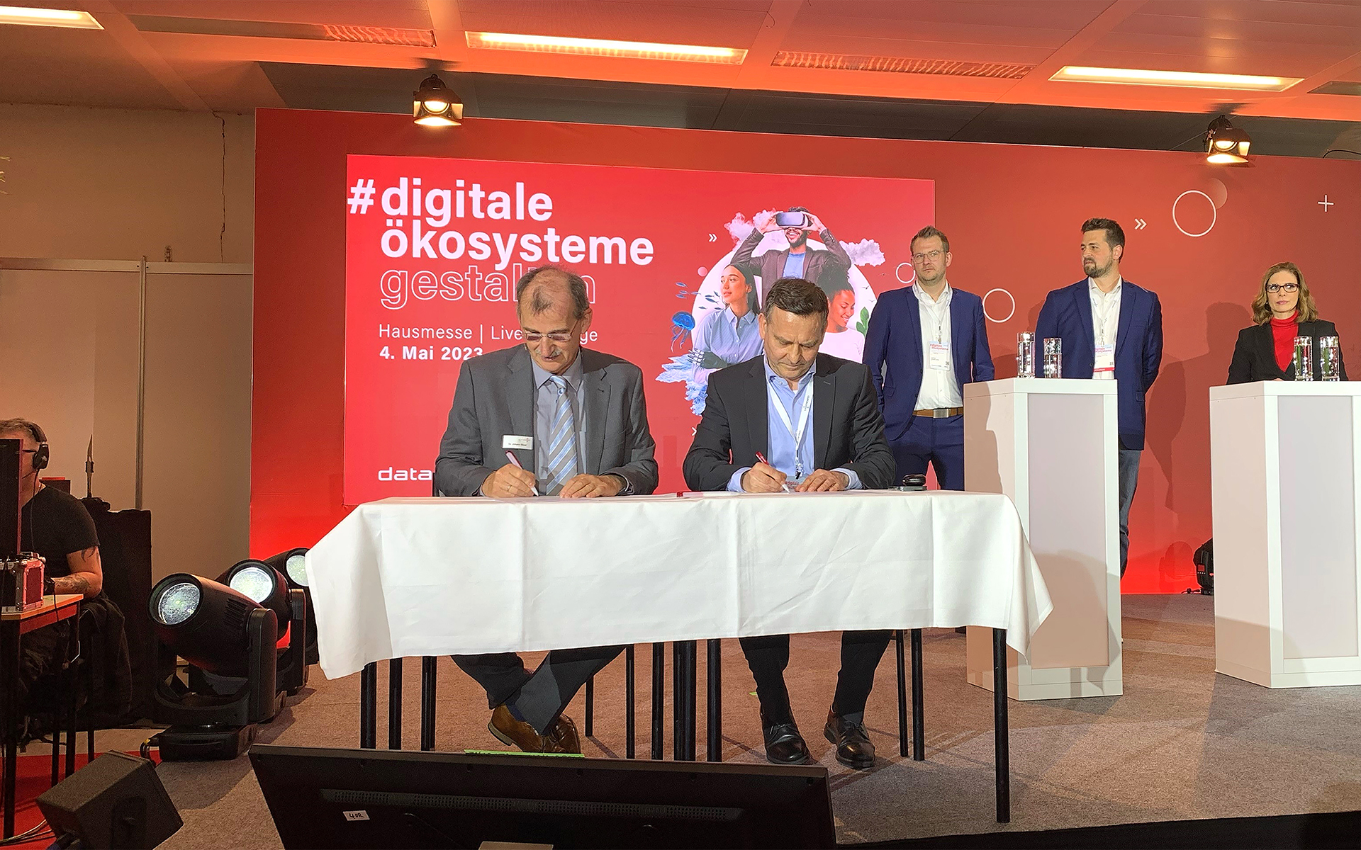 Unterzeichnung der Kooperationsvereinbarung auf der Dataport-Hausmesse (vorne v.l.n.r.): Dr. Johann Bizer, Vorstandsvorsitzender Dataport, und Dr. Martin Deeg, Senior Vice President Customer Solutions BWI; (hinten v.l.n.r.): Andreas Reckert-Lodde, Leiter der Arbeitsgruppe Cloud Computing und Digitale Souveränität und Projektgruppenleiter Zentrum für Digitale Souveränität Bundesministerium des Innern und für Heimat, Moritz Dörr, Programmleiter dPhoenixSuite Dataport, sowie Stefanie Dreyer, Moderatorin.