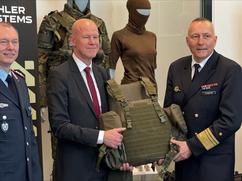Thomas Homberg (mitte) von Mehler Vario Systems übergibt die 100.000ste Schutzweste des MOBAST-Systems an Carsten Stawitzki, den Abteilungsleiter Ausrüstung im BMVg.