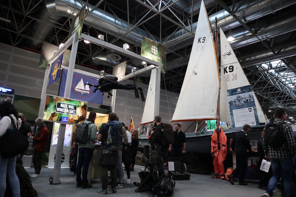 Der Stand der Bundeswehr auf der Wassersportmesse "boot" in Düsseldorf mit interessierten Messebesuchern und einem Segelkutter der Marine im Hintergrund.