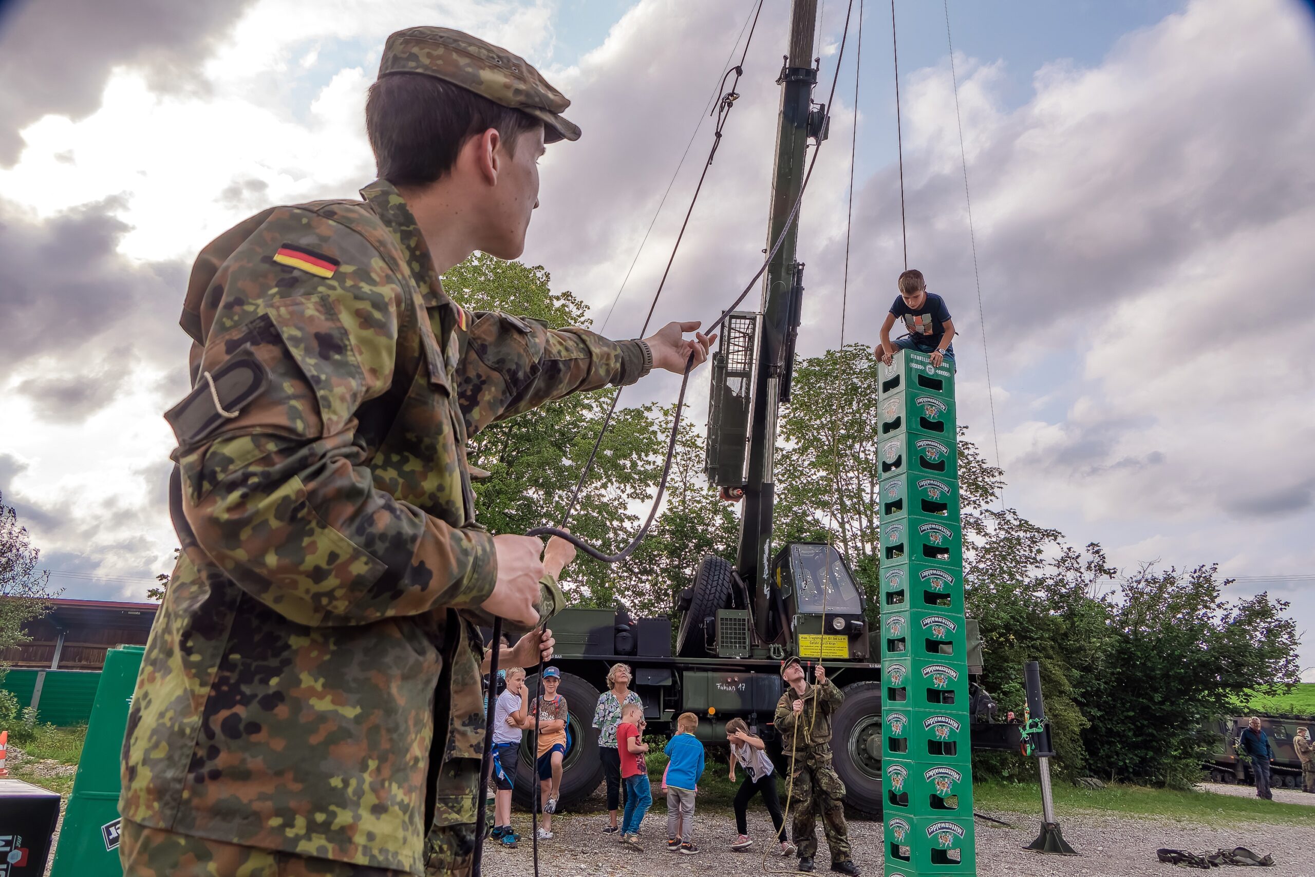 Wackliges Bauwerk: Am Klettergurt gesichert arbeitet sich ein Junge geschickt Kasten für Kasten in die Höhe.