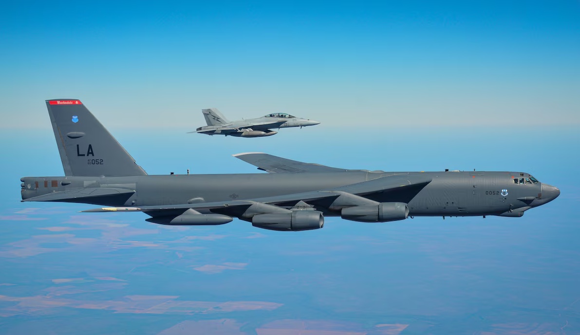 B-52 Bomber wird von Kampfjet begleitet.